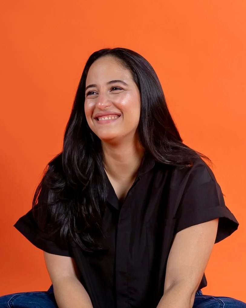 Cesarina Rizik sonriendo sobre fondo naranja
